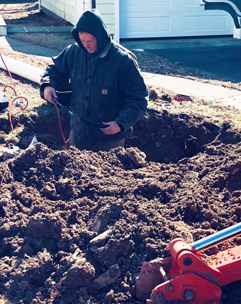 A man in a hooded jacket is digging in the dirt