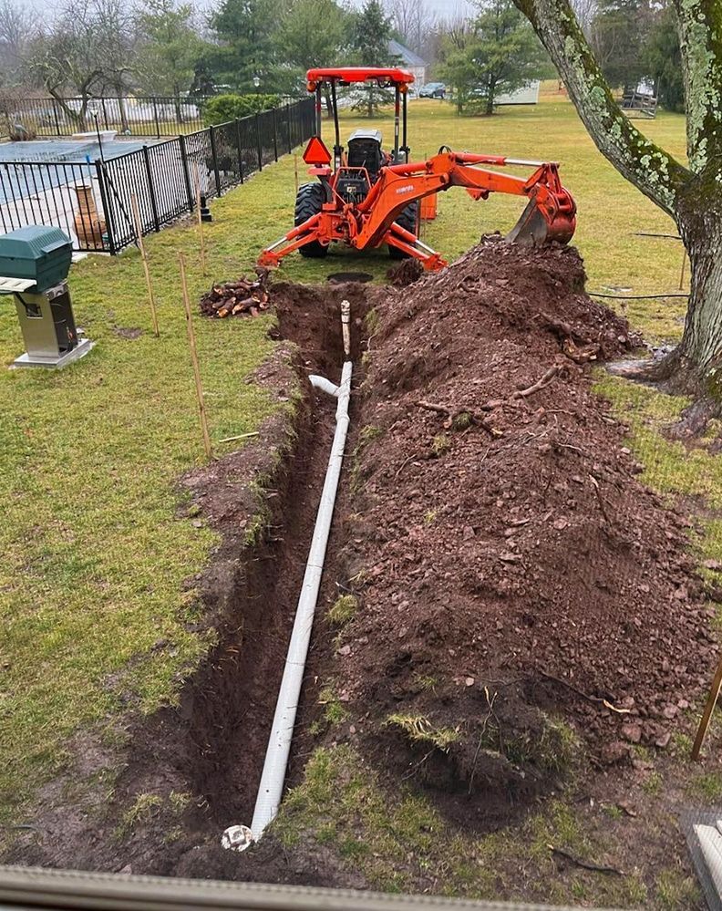 A tractor is digging a hole in the ground to install a pipe.