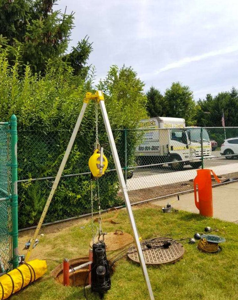 A manhole cover is being installed in a yard with a truck in the background.
