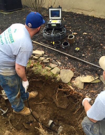 Two men are looking at a camera in the dirt.