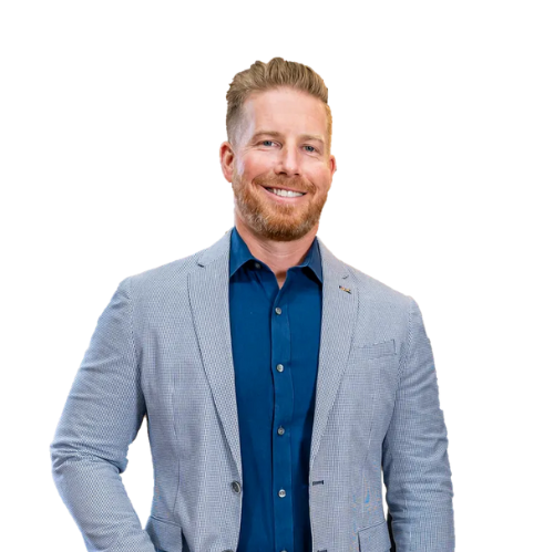 Smiling man with red hair and beard in blue shirt and grey blazer.