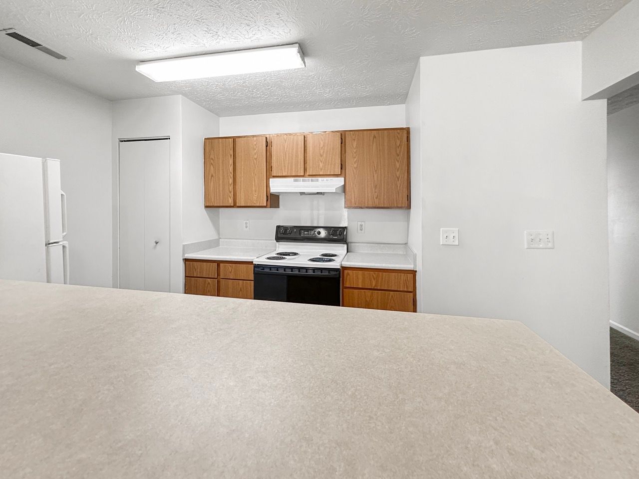 A kitchen with wooden cabinets , a stove , and a refrigerator.