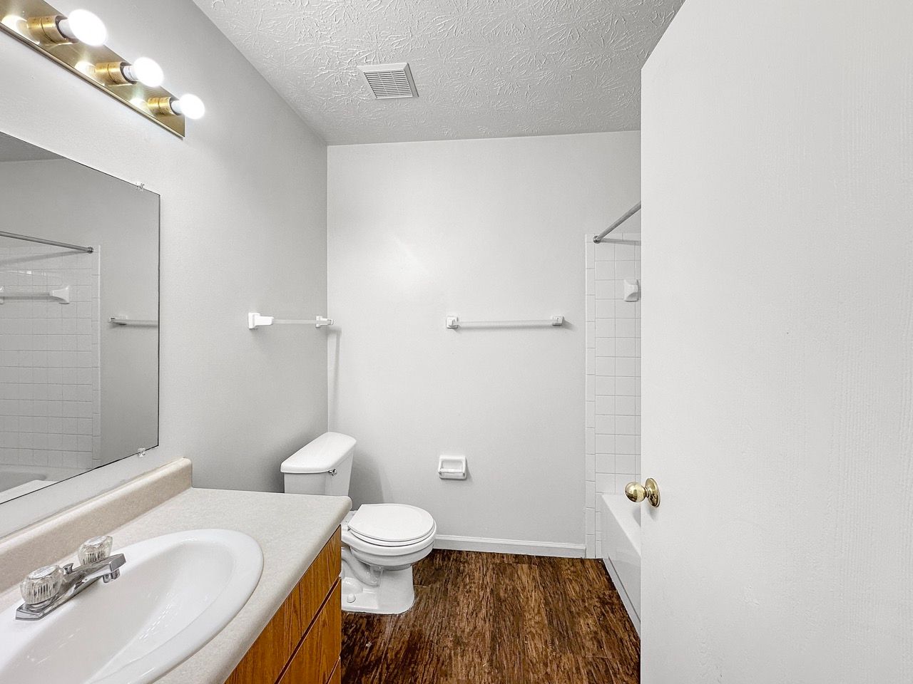 A bathroom with a toilet , sink , mirror and bathtub.