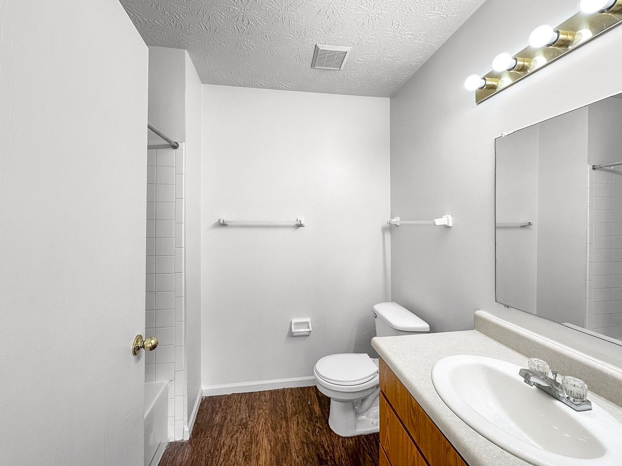 A bathroom with a toilet , sink , and mirror.