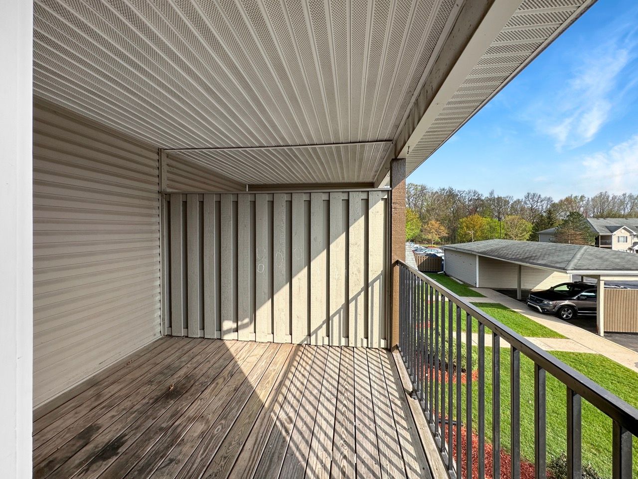 An empty balcony with a metal railing and a wooden floor.