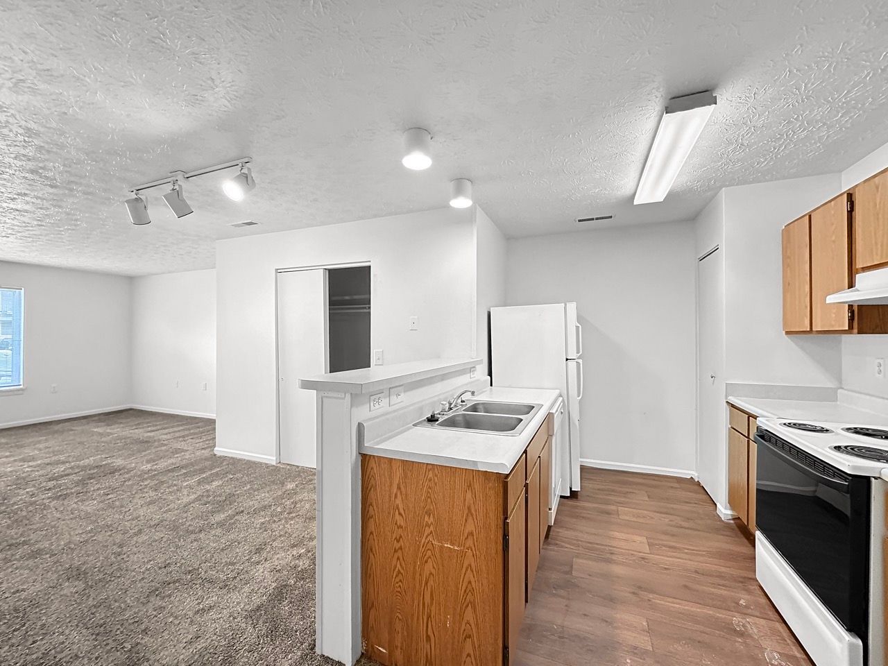 A kitchen with a refrigerator , stove , sink , and cabinets.