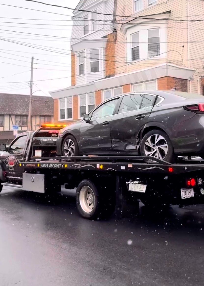 A car is being towed by a tow truck in a parking lot.