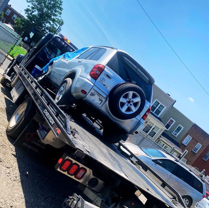A tow truck is carrying two vans down a snowy road.