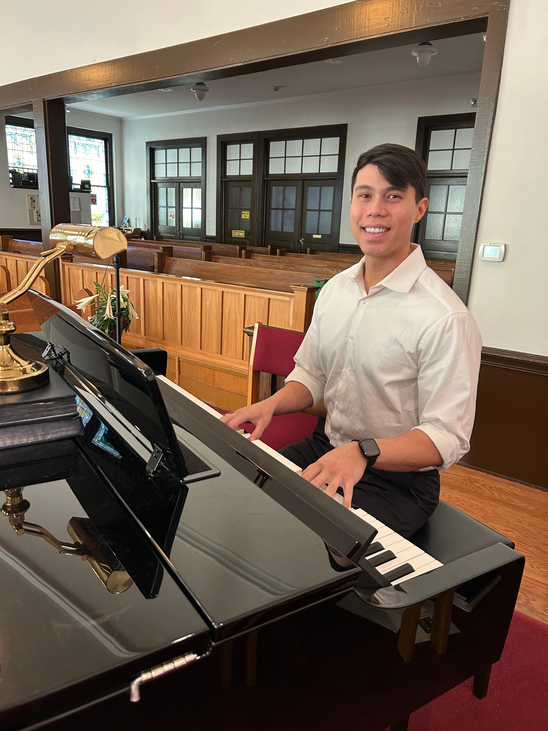 A pianist in a white shirt is playing a piano in a church