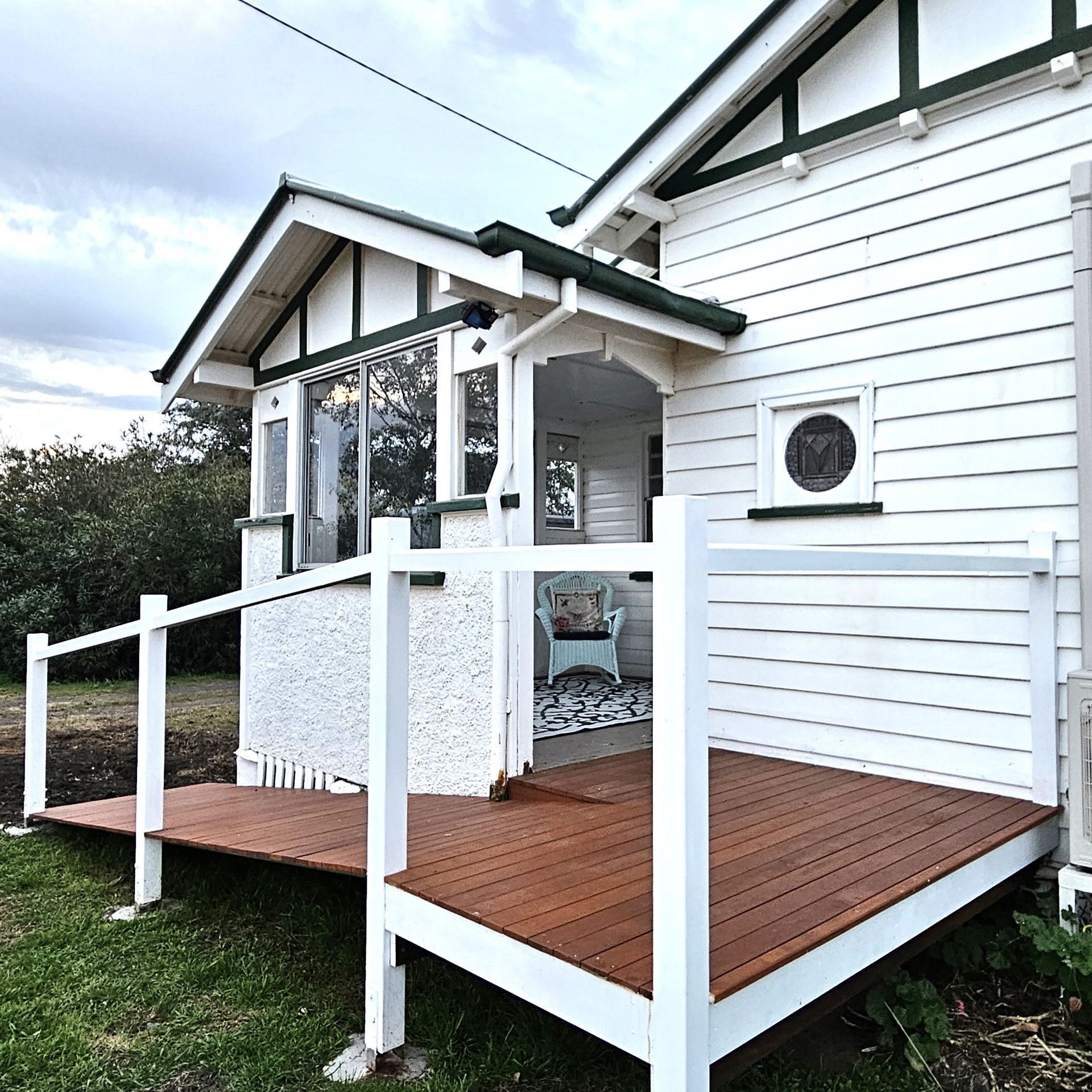 A white farmhouse with a wooden entry ramp in front of it