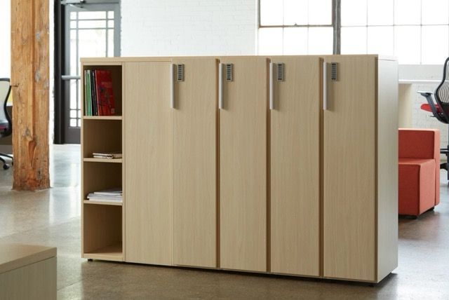 Modern beige modular office storage wall with cabinets, shelves, and a bench-style desk on a white background