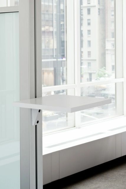 Side view of a white adjustable monitor mount with a black screen and attached cable on a pole.