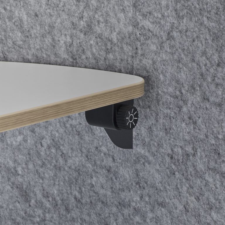 White tabletop with black under-desk adjustable mounting knob against gray felt background