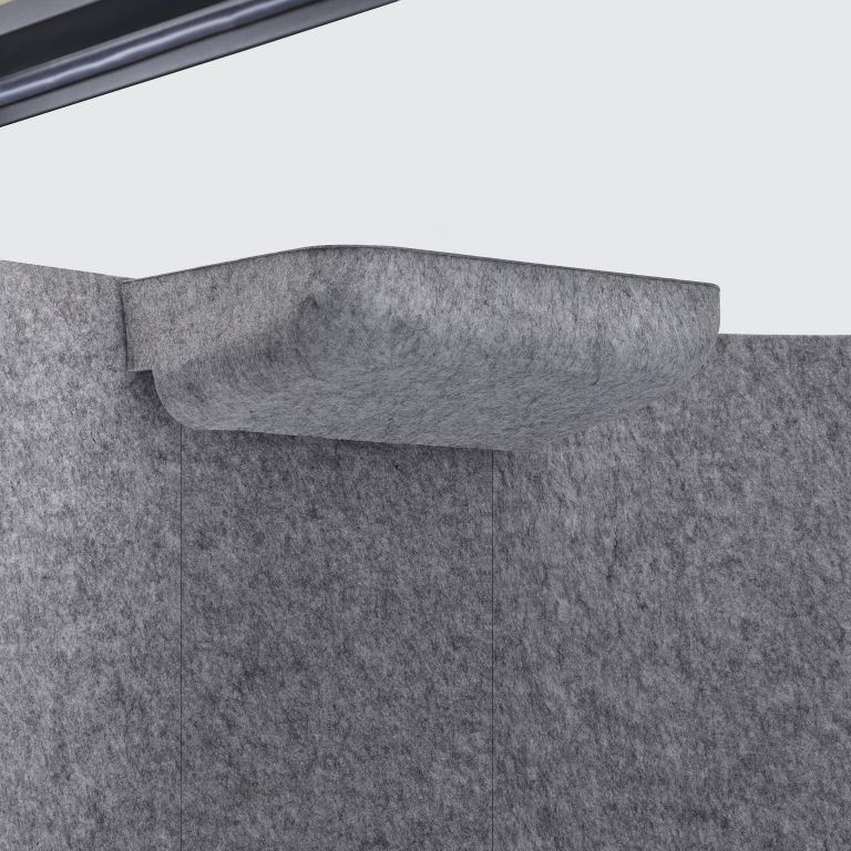 Gray upholstered couch corner with a folded cushion or blanket on top