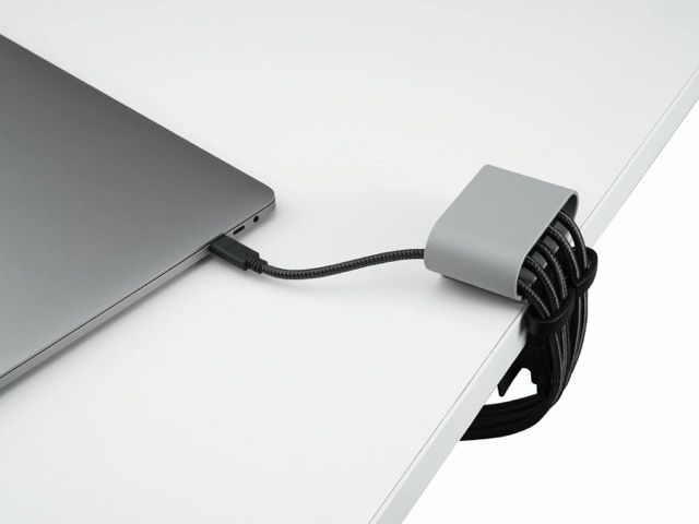 Small black and gray electronic device with blue indicators on a white surface