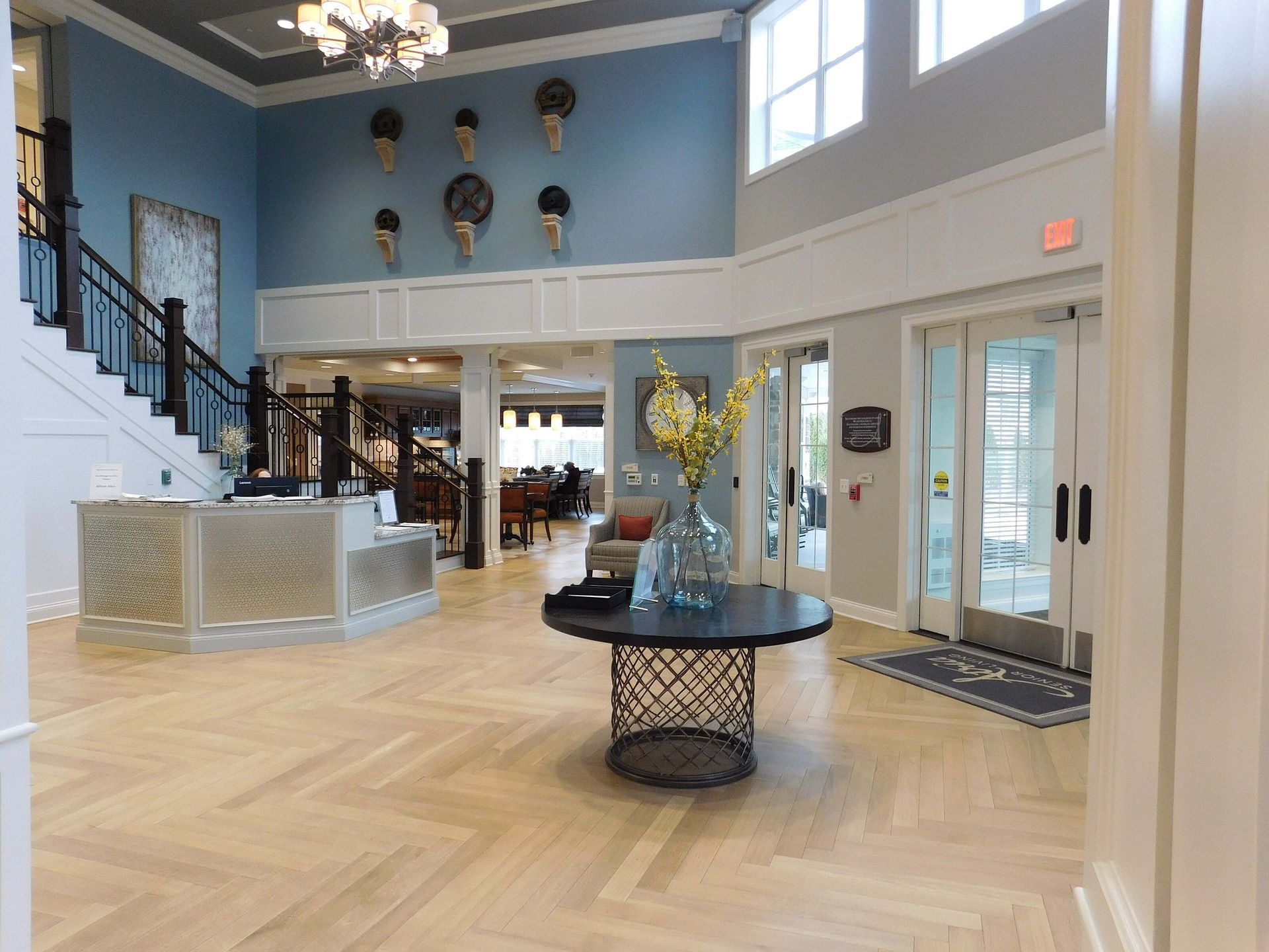 Bright airy lobby with staircase, marble desk, blue walls, and patterned rug.