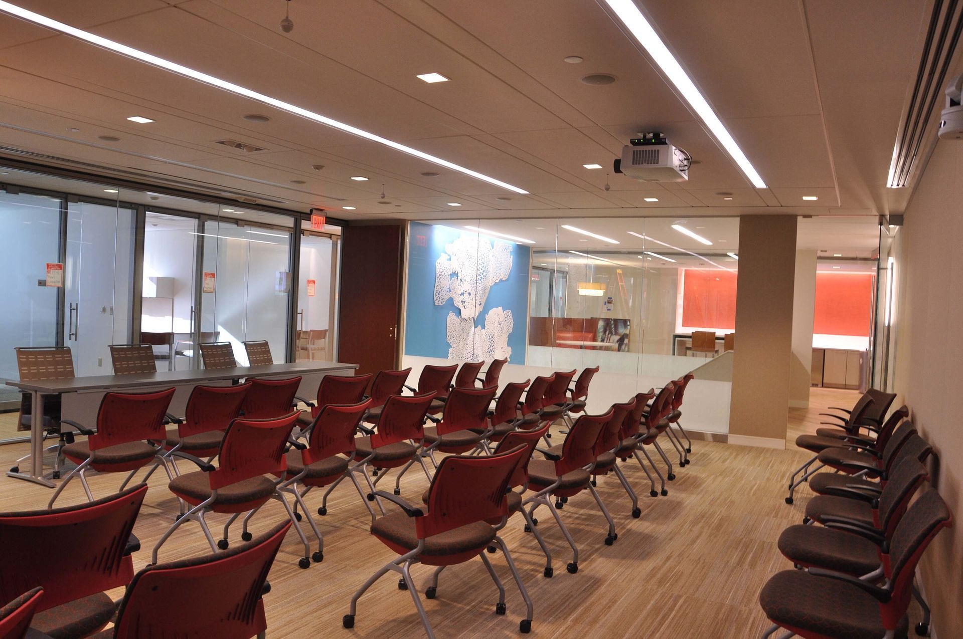 Empty waiting area with rows of maroon chairs, large windows, and overhead lights in a modern terminal.