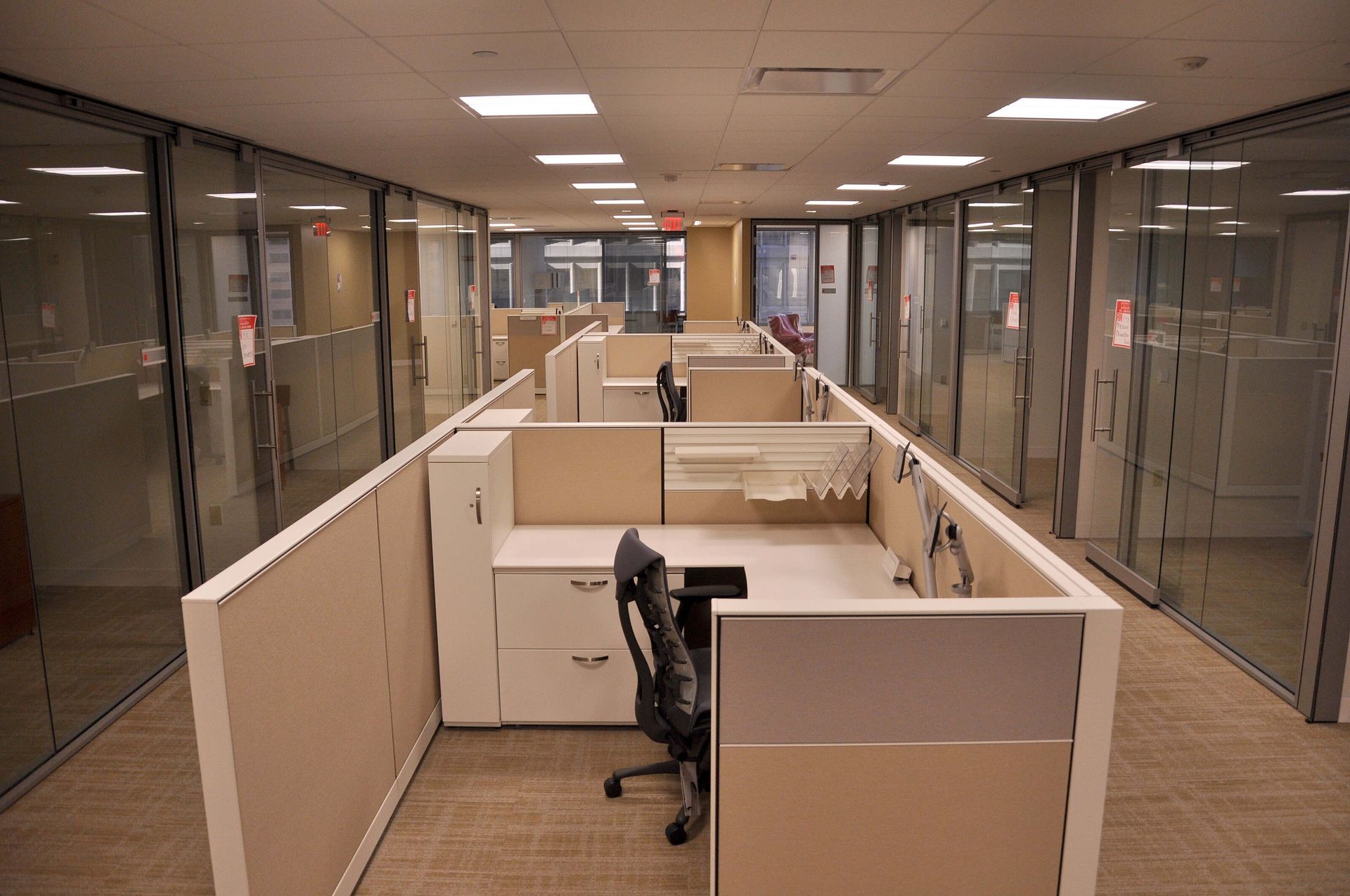 Empty office hallway with beige cubicles and glass-walled offices on both sides