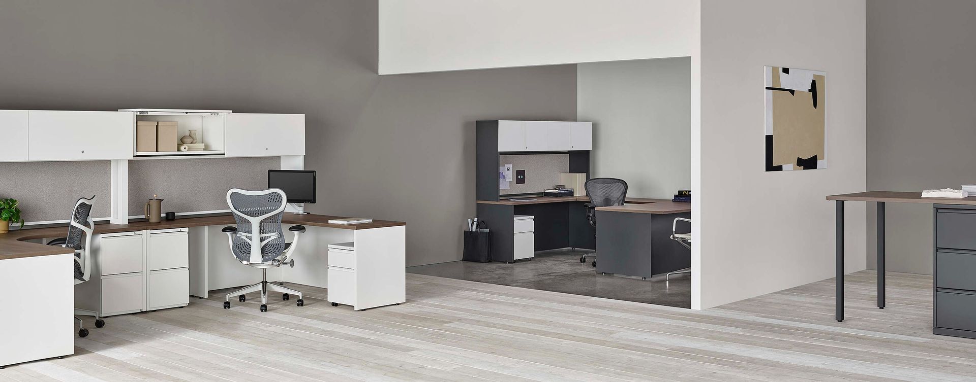 Modern open-plan kitchen and living area with white cabinets, gray walls, and a dining table in the foreground