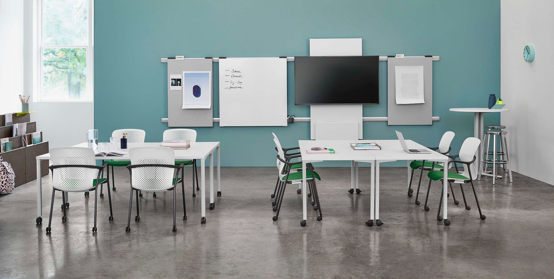 Modern classroom with desks, whiteboard, TV, and green chairs against a teal wall