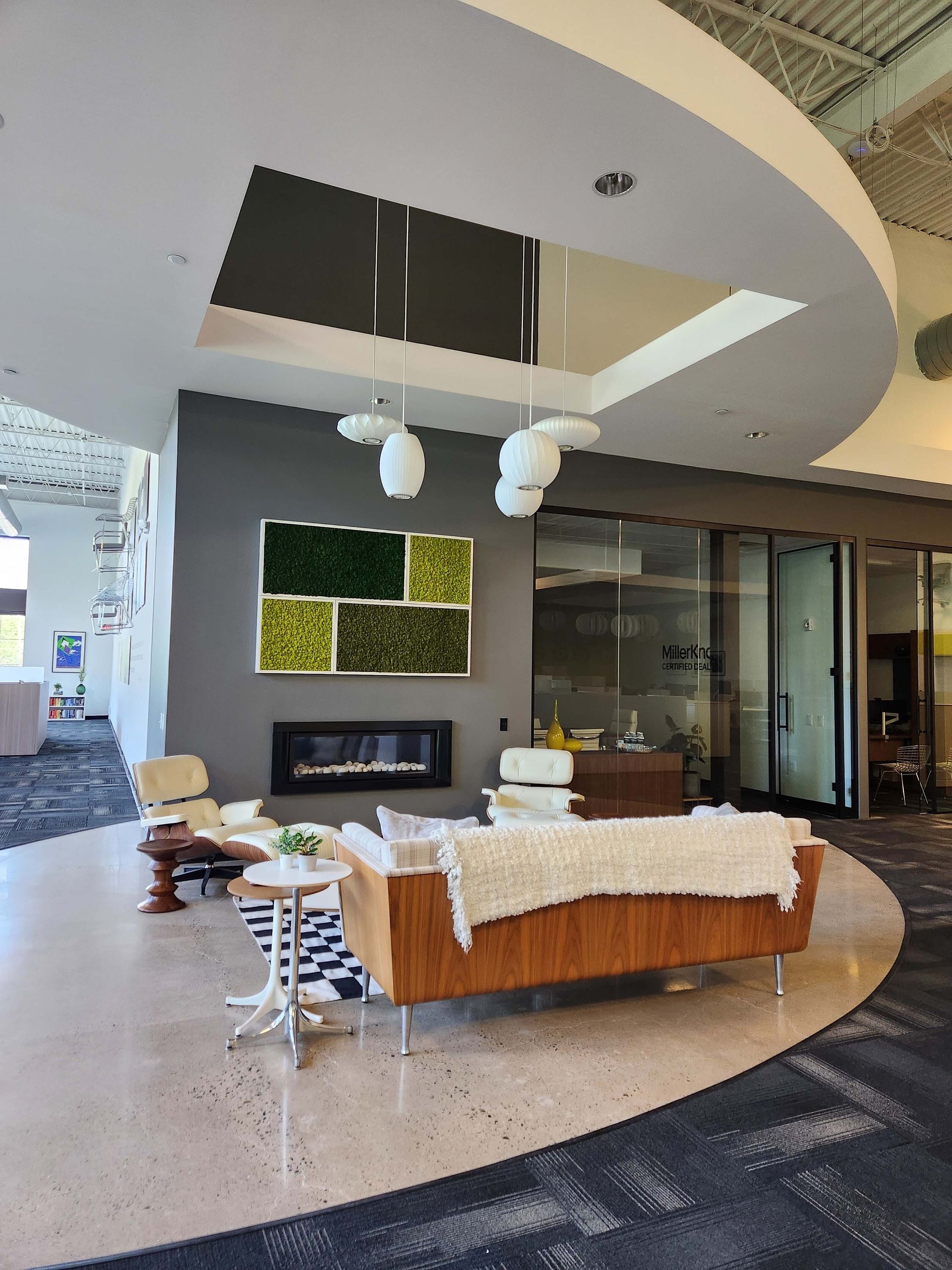 Modern living room with curved ceiling, fireplace, glass wall, and white-and-brown sofa set on a circular rug
