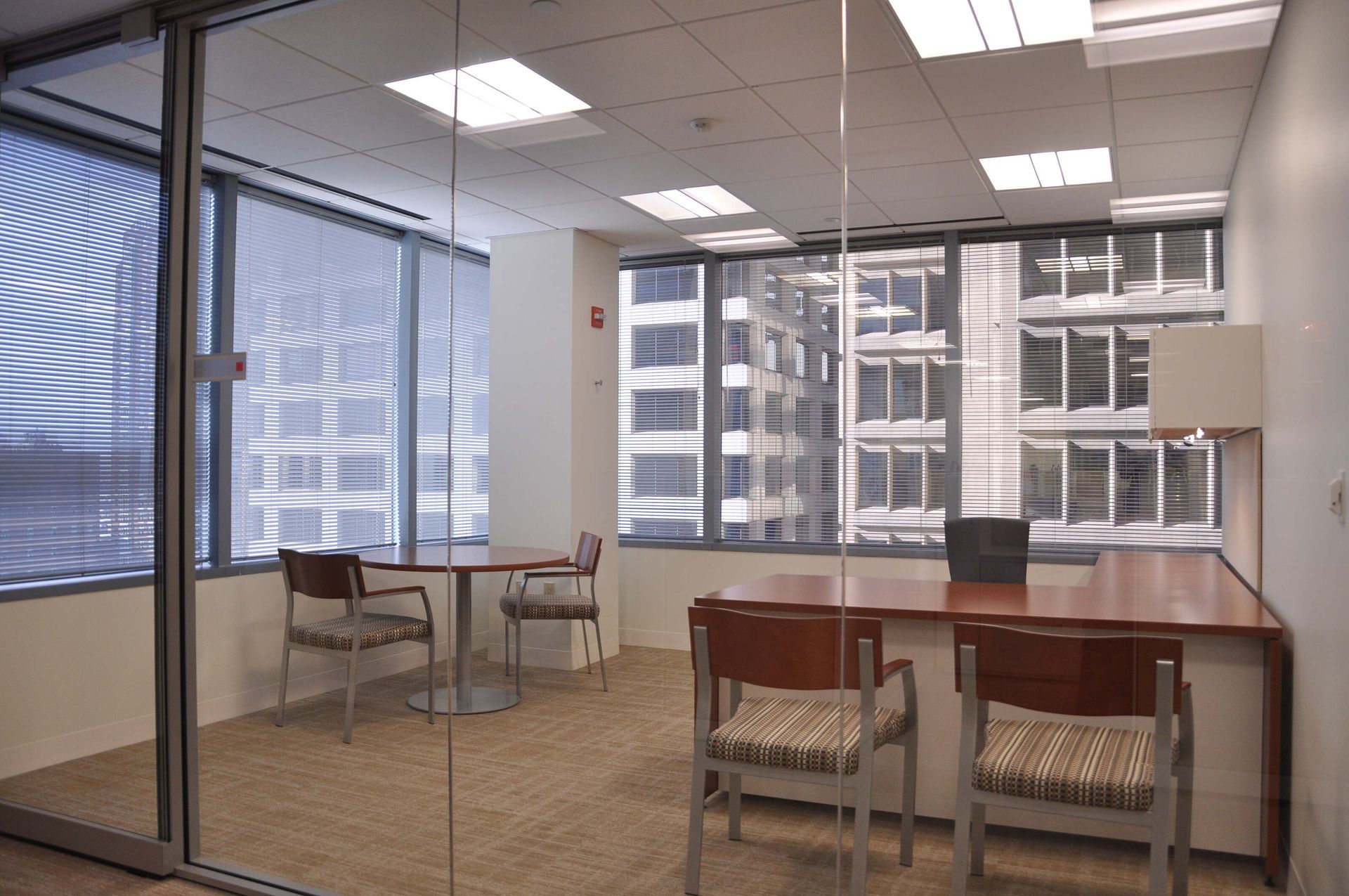 Empty office with desks, chairs, and large windows overlooking city buildings
