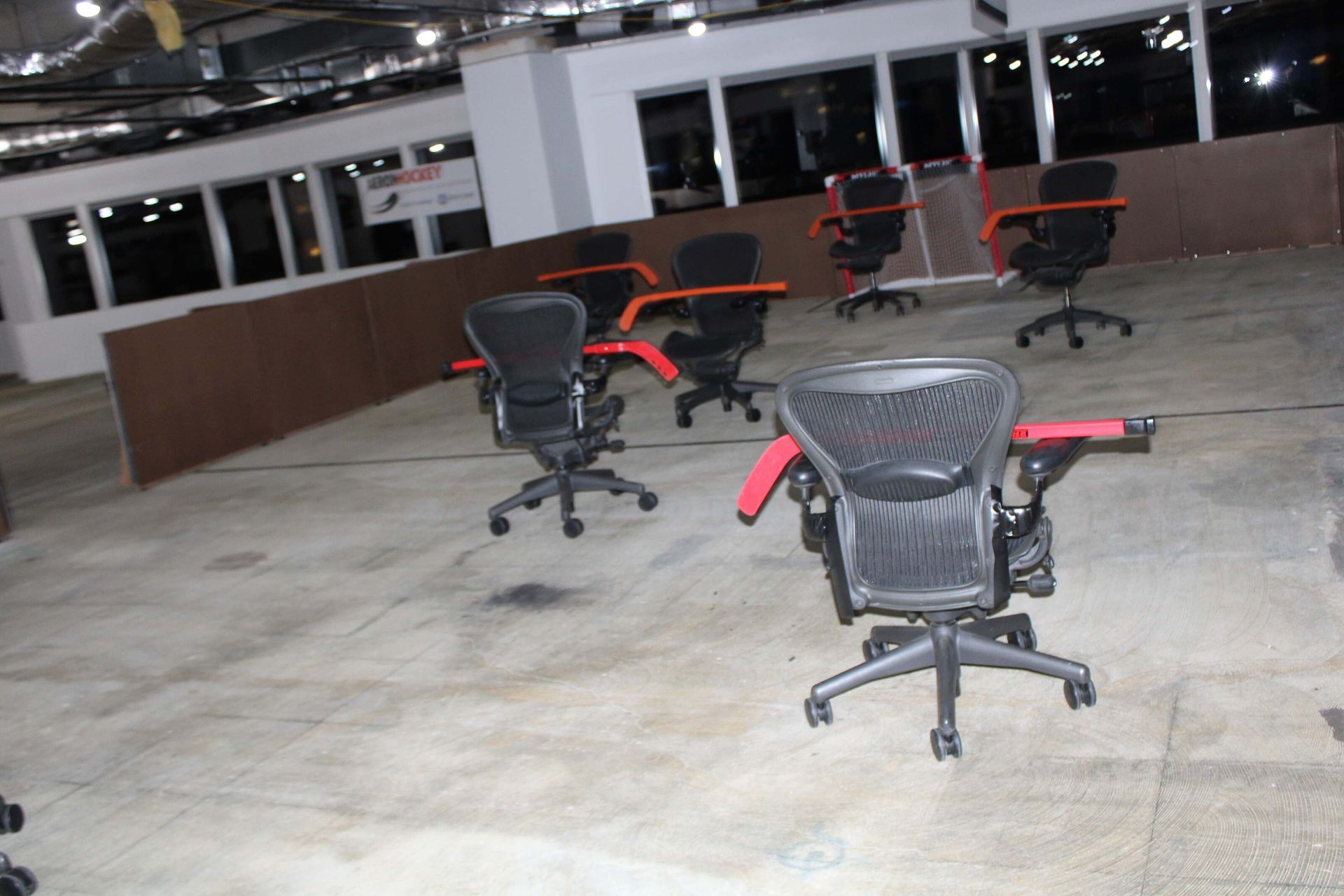 Empty office space with several black and orange office chairs on a concrete floor