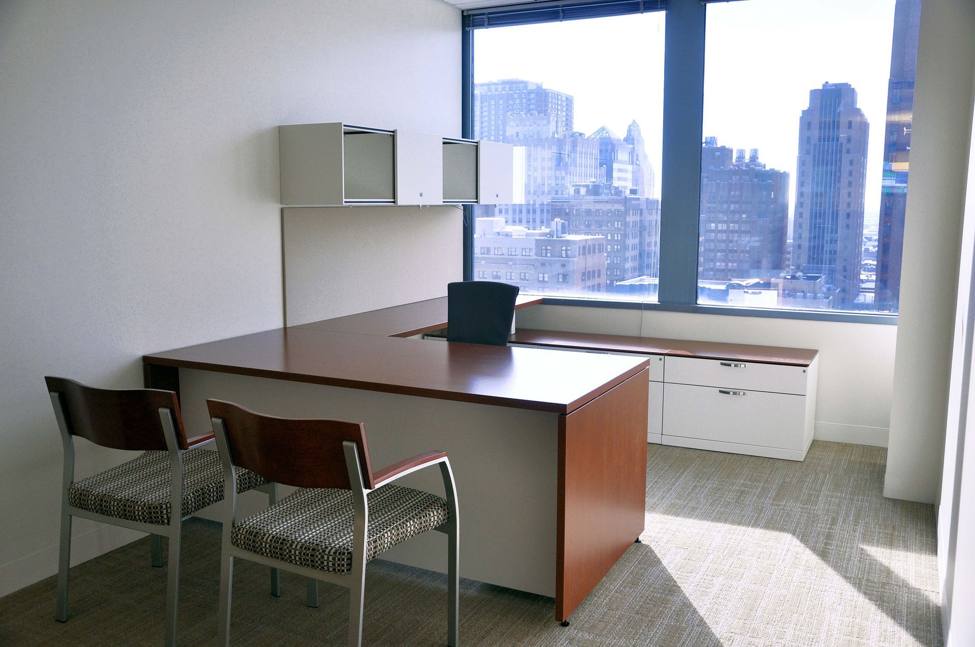 Empty office with desk, chair, cabinets, and large window overlooking a city skyline