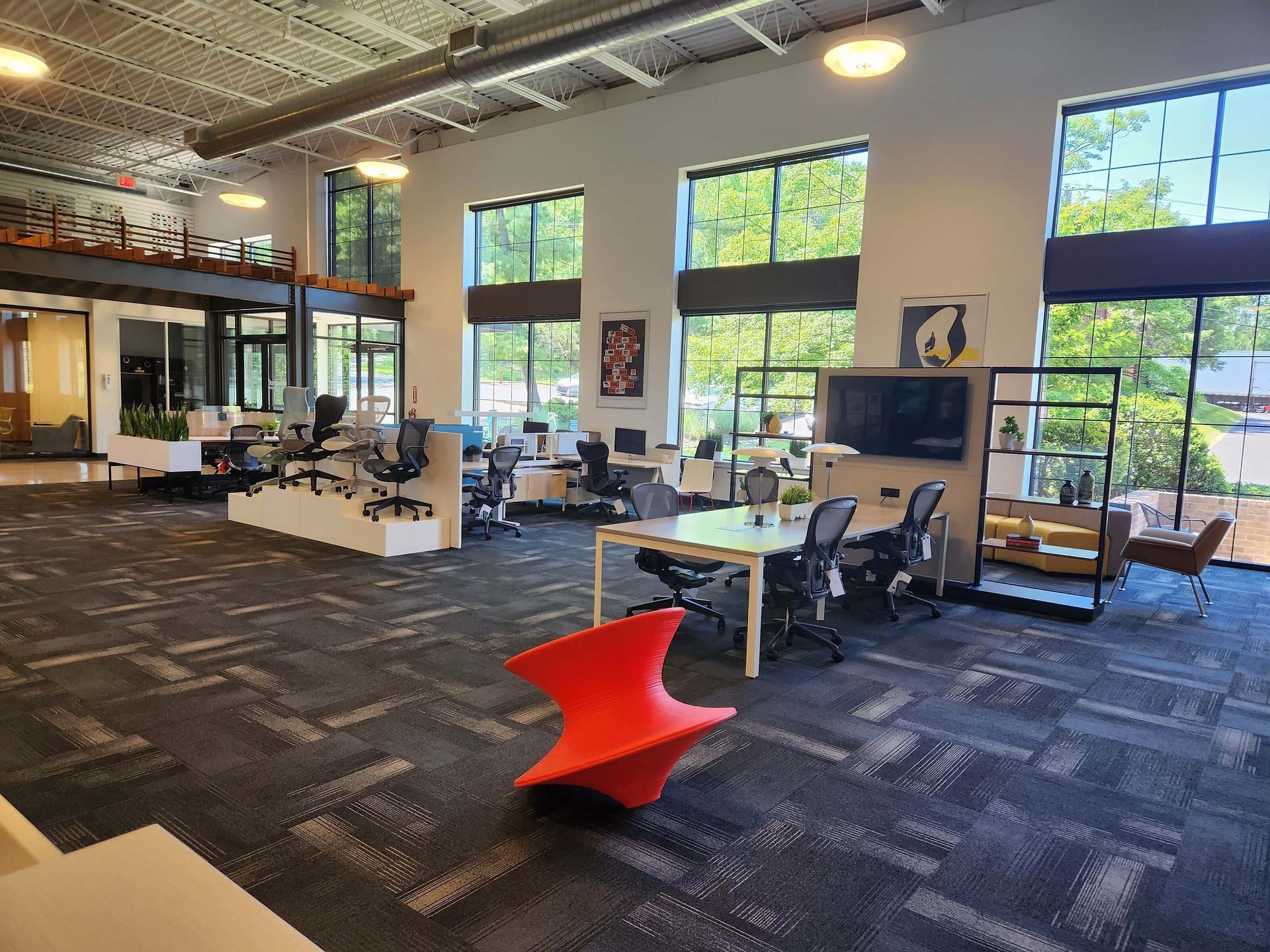 Modern open office with desks, large windows, and a bright red chair in the foreground