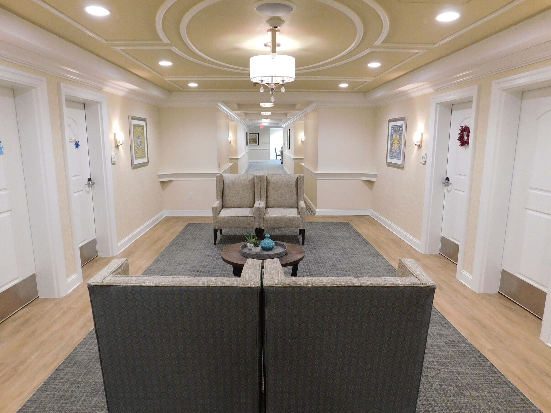 Elegant hotel hallway with beige seating, chandelier lighting, and patterned carpet￼