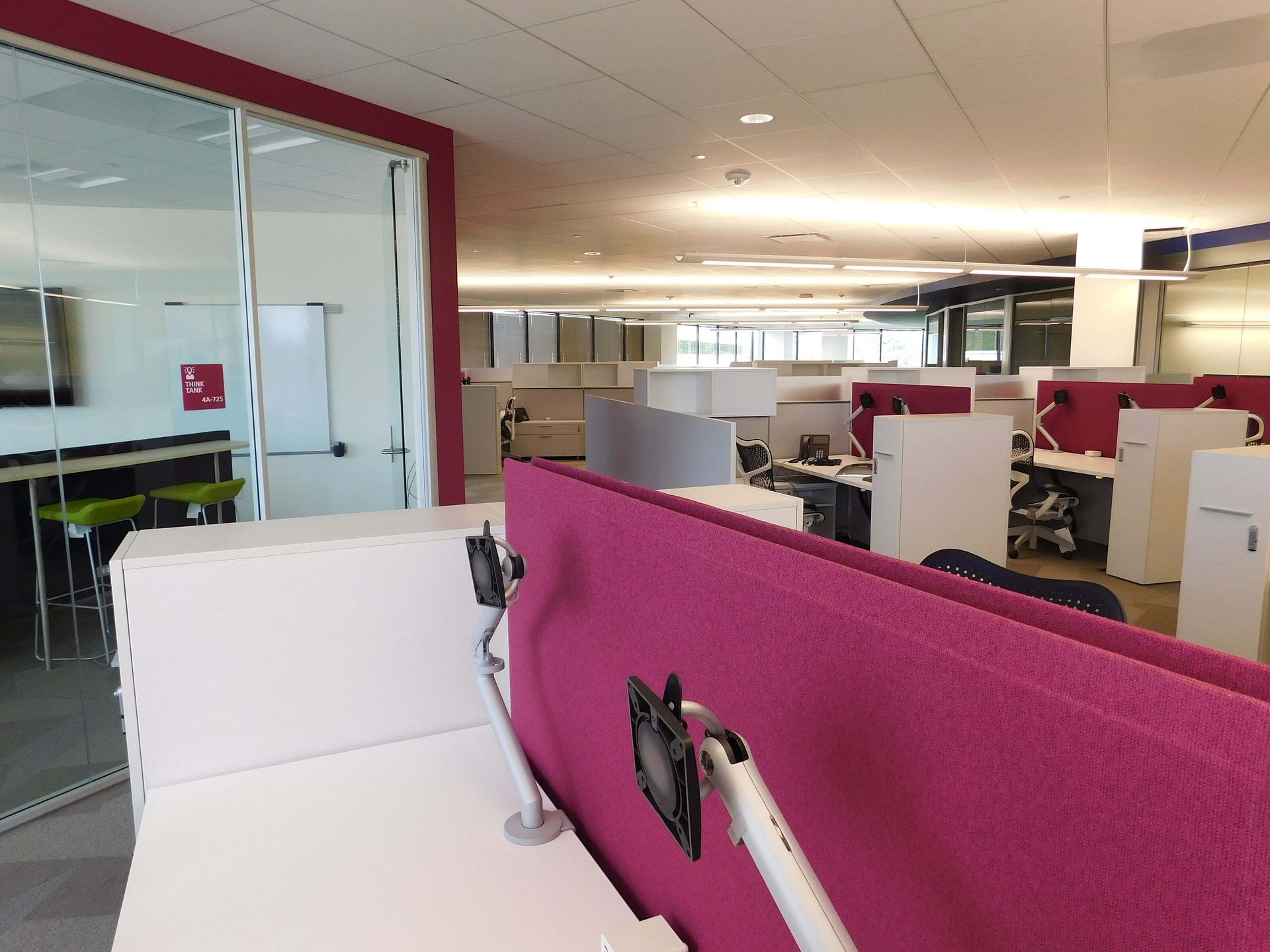 Modern office cubicles with pink partitions and glass-walled meeting rooms￼