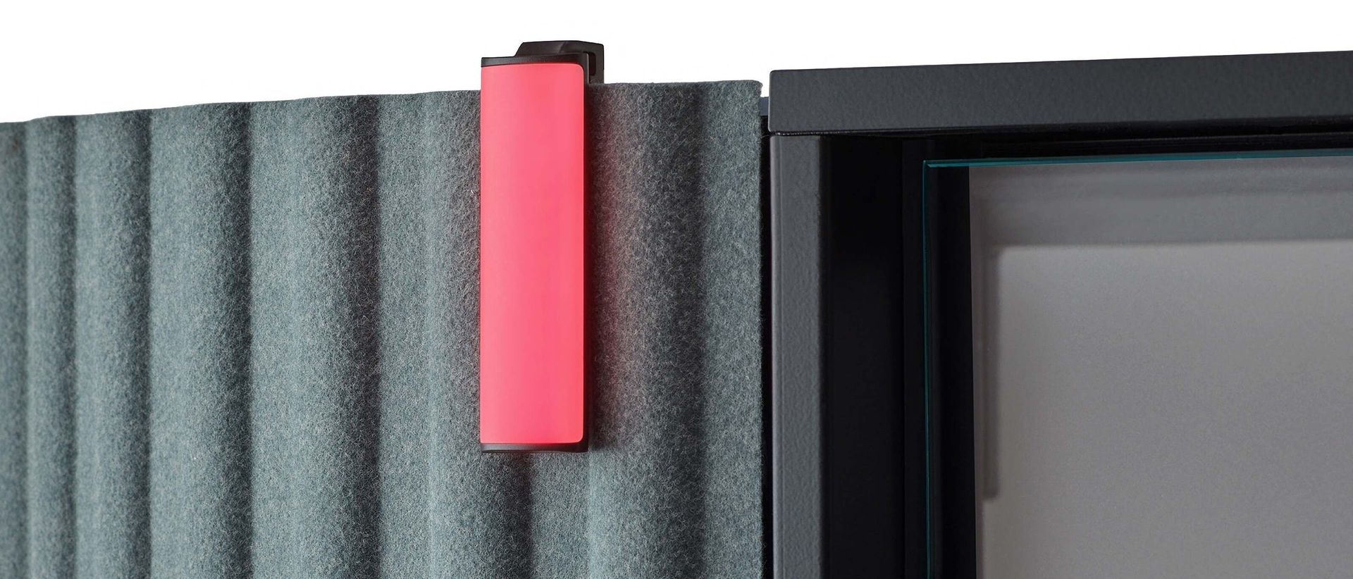 Pink wall light mounted beside a window on a gray corrugated exterior wall