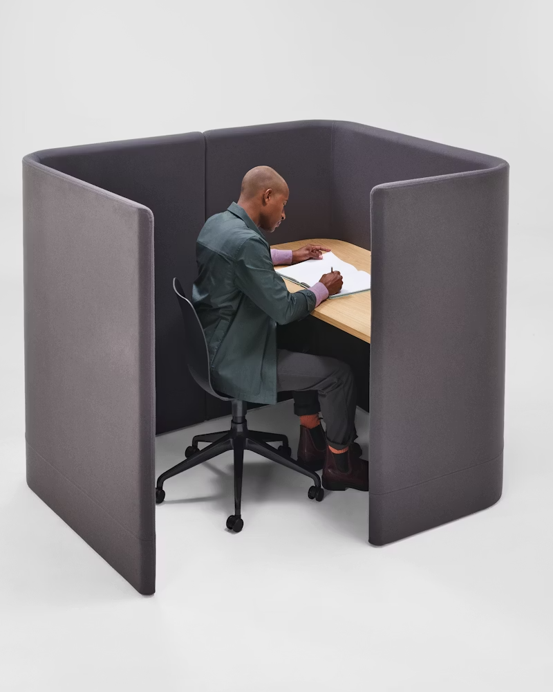 Two small office privacy booths with chairs, one burgundy and one gray, on a white background