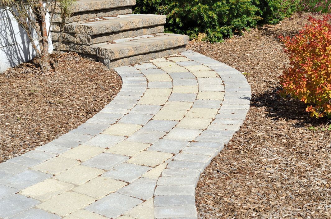 A stone walkway leading to a stone staircase in a garden.