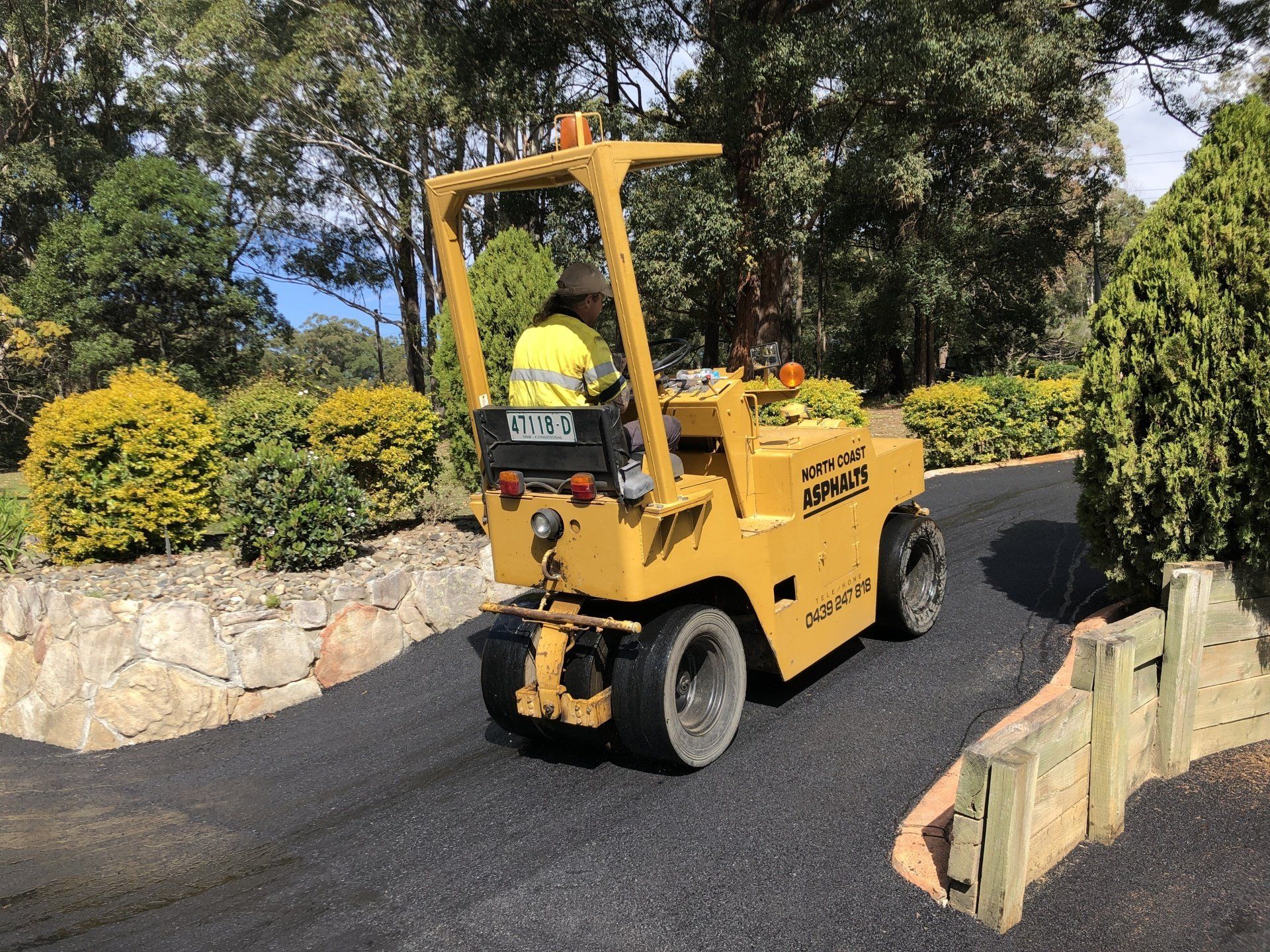 A man is driving a yellow forklift down a road.