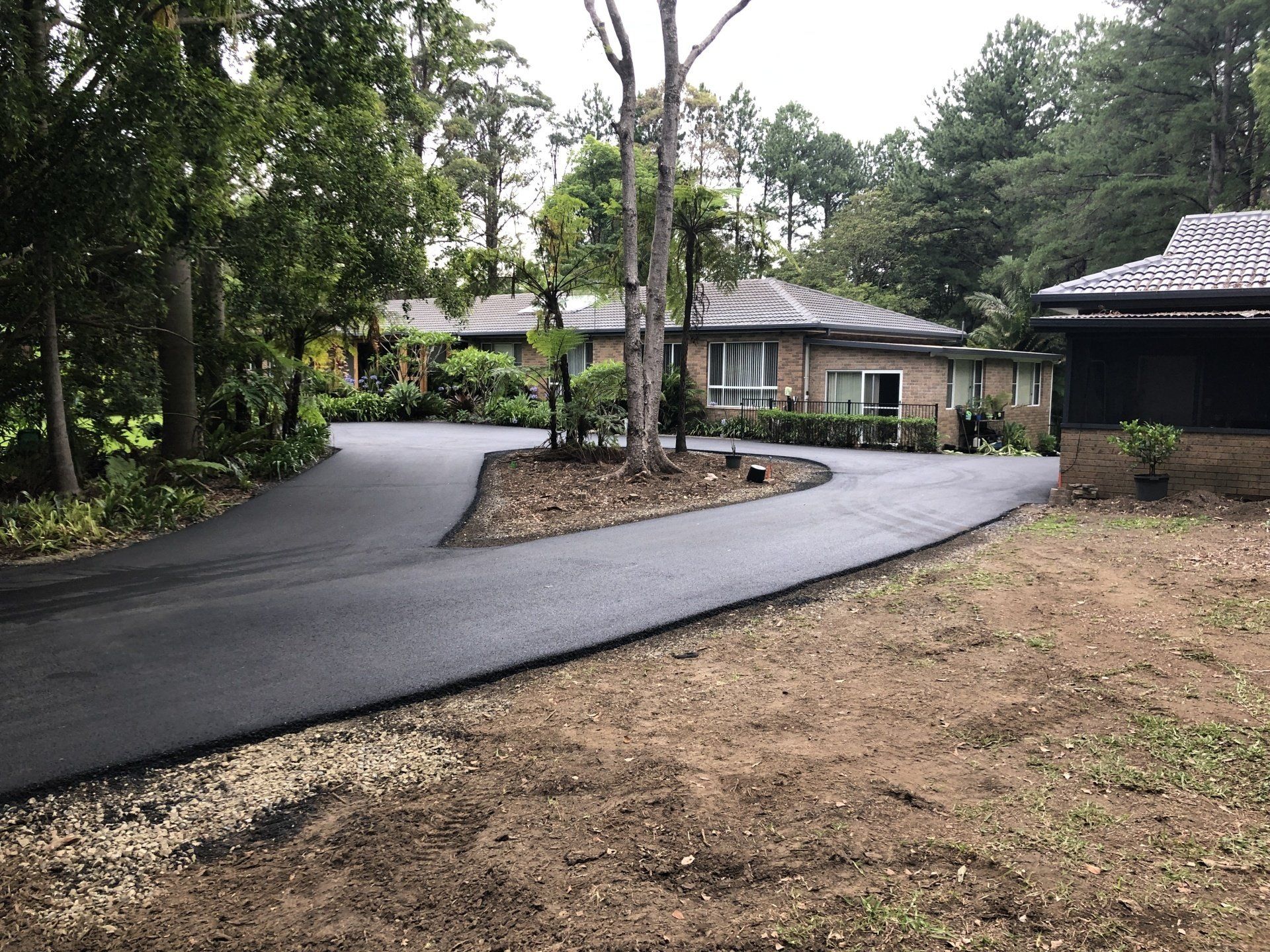 A driveway leading to a house surrounded by trees.
