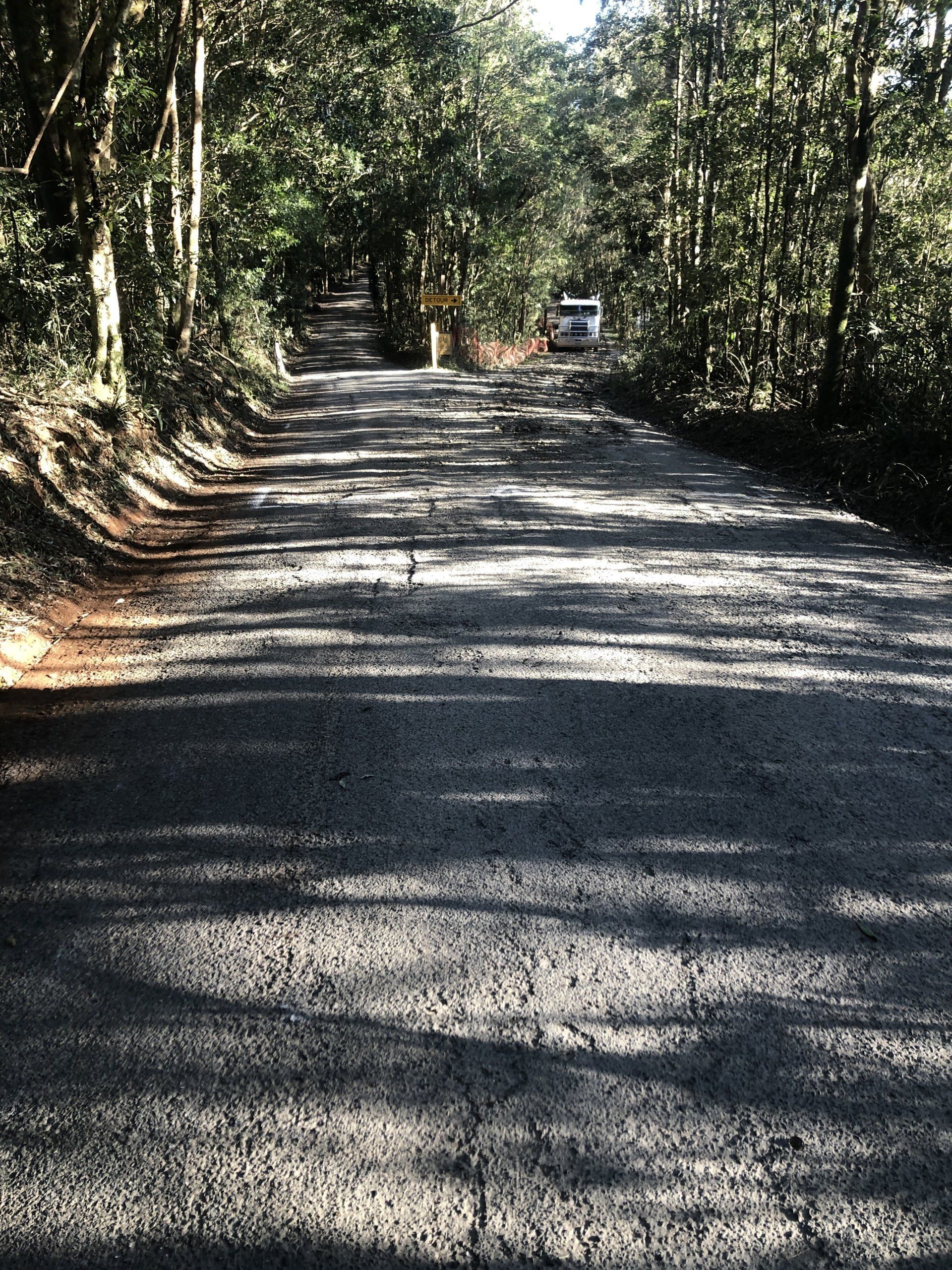 A car is driving down a road surrounded by trees.