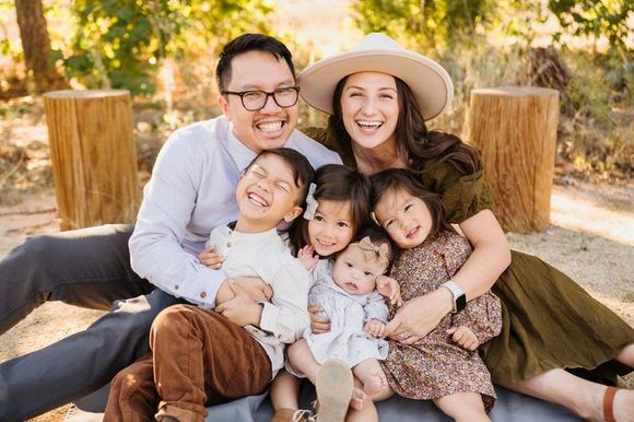 A family is posing for a picture while sitting on a blanket.