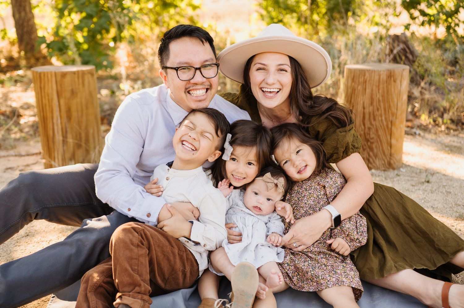 A family is posing for a picture while sitting on a blanket.