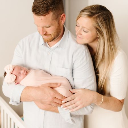 A man and woman are holding a newborn baby in their arms