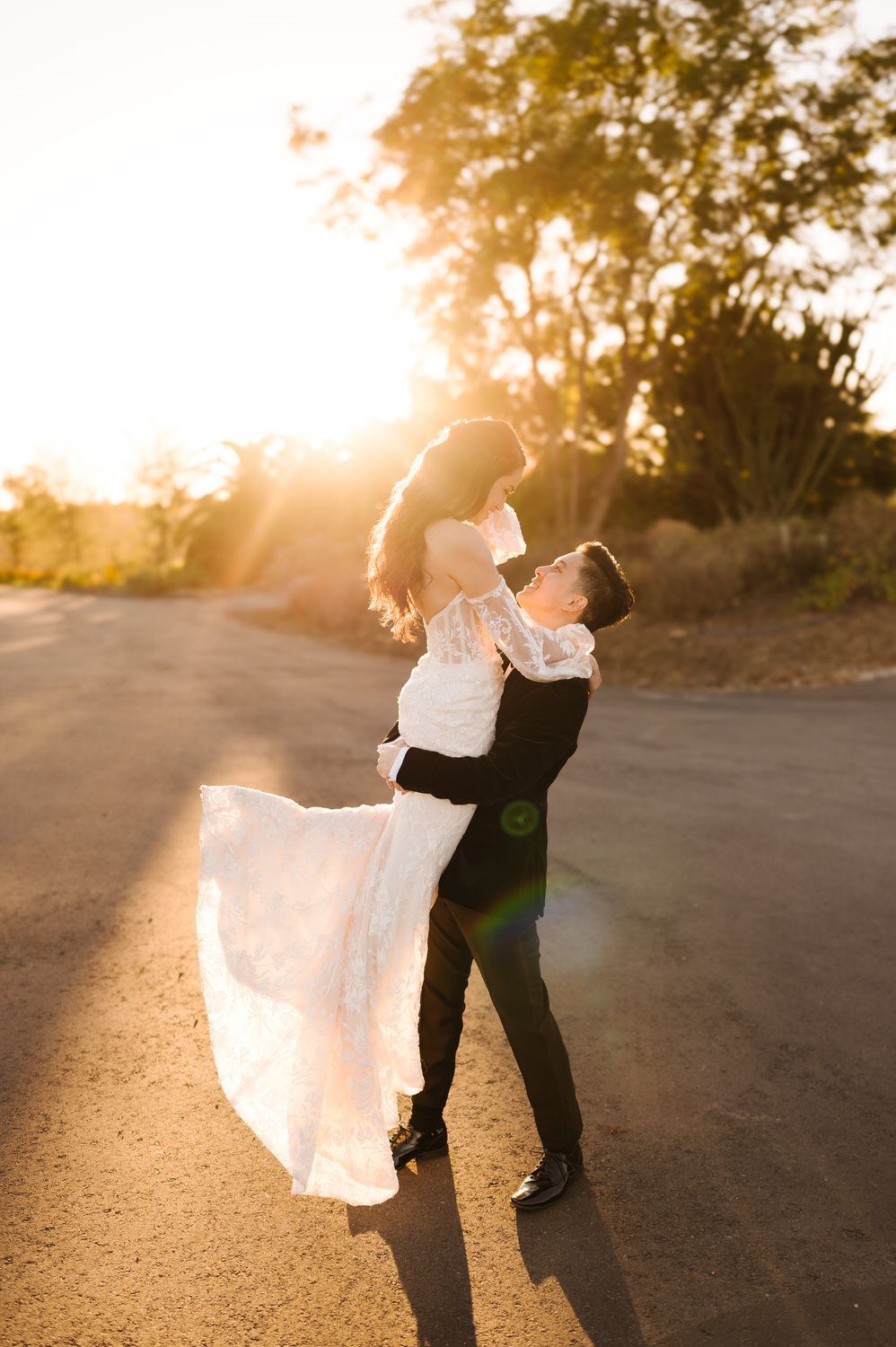 Couple dancing outdoors at sunset, bride’s white dress flowing in warm light