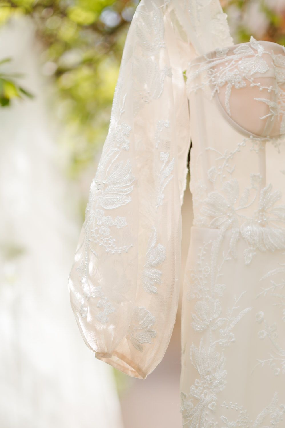 A close up of a white lace dress hanging on a hanger.