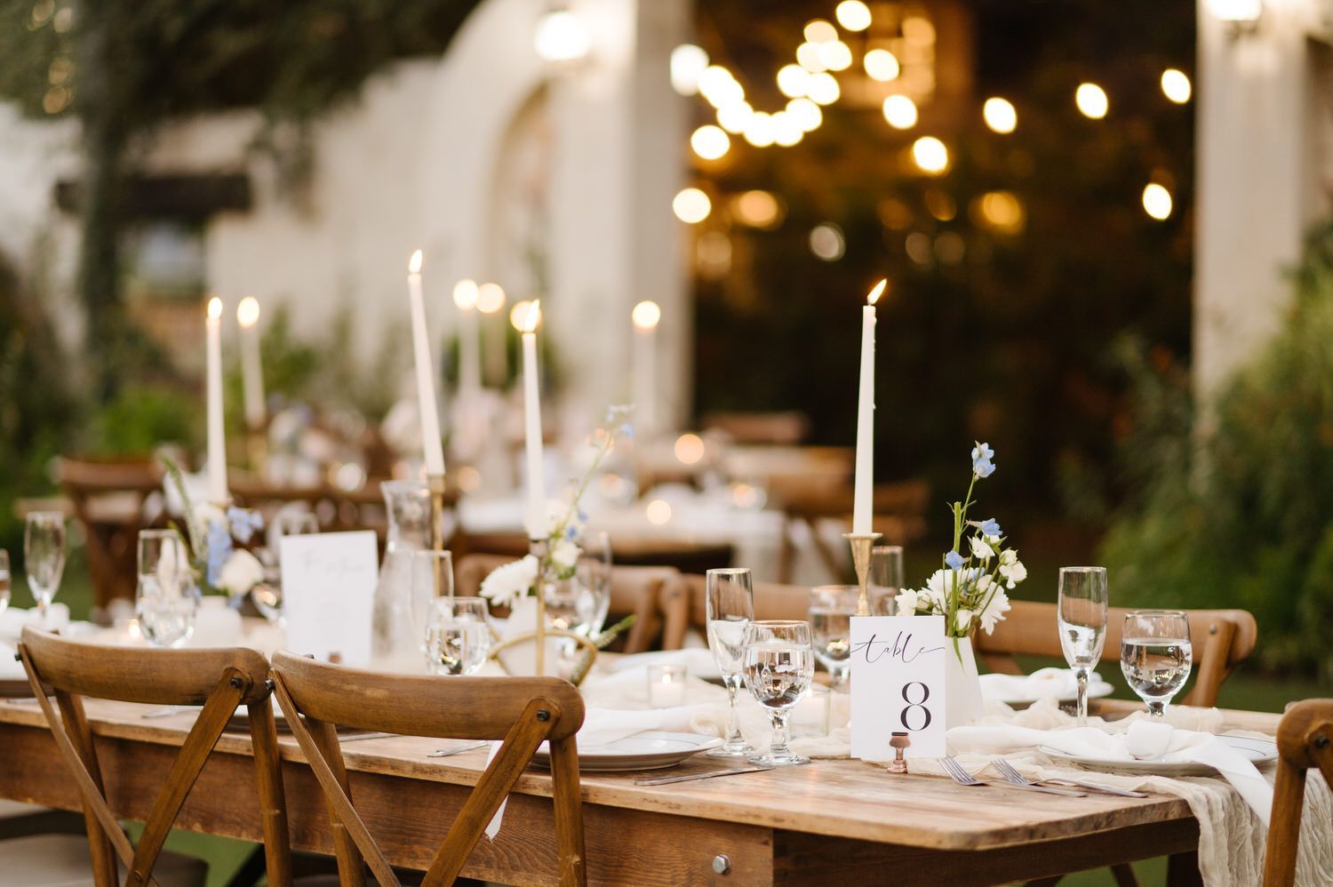 A table set for a wedding reception with candles and wine glasses.