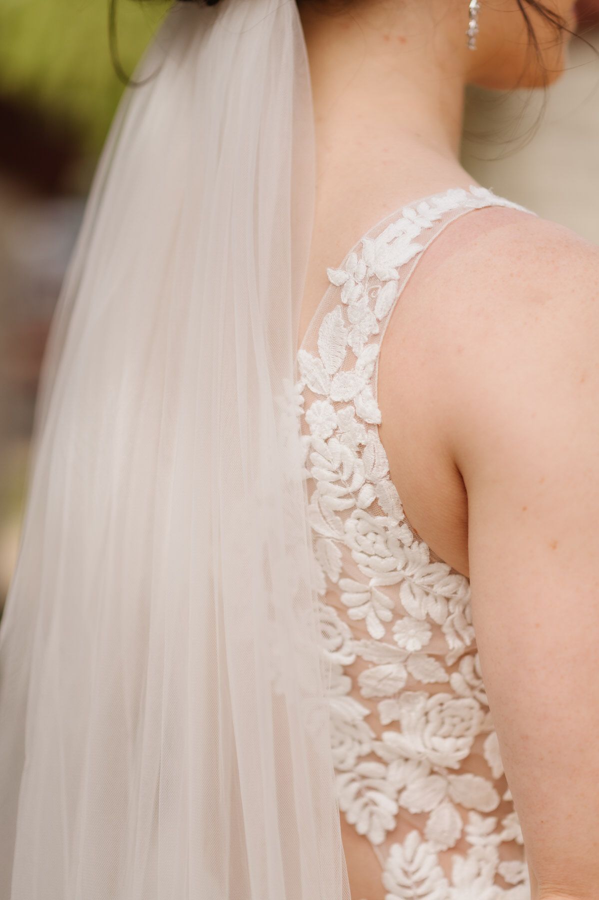 The back of a bride wearing a wedding dress and veil.