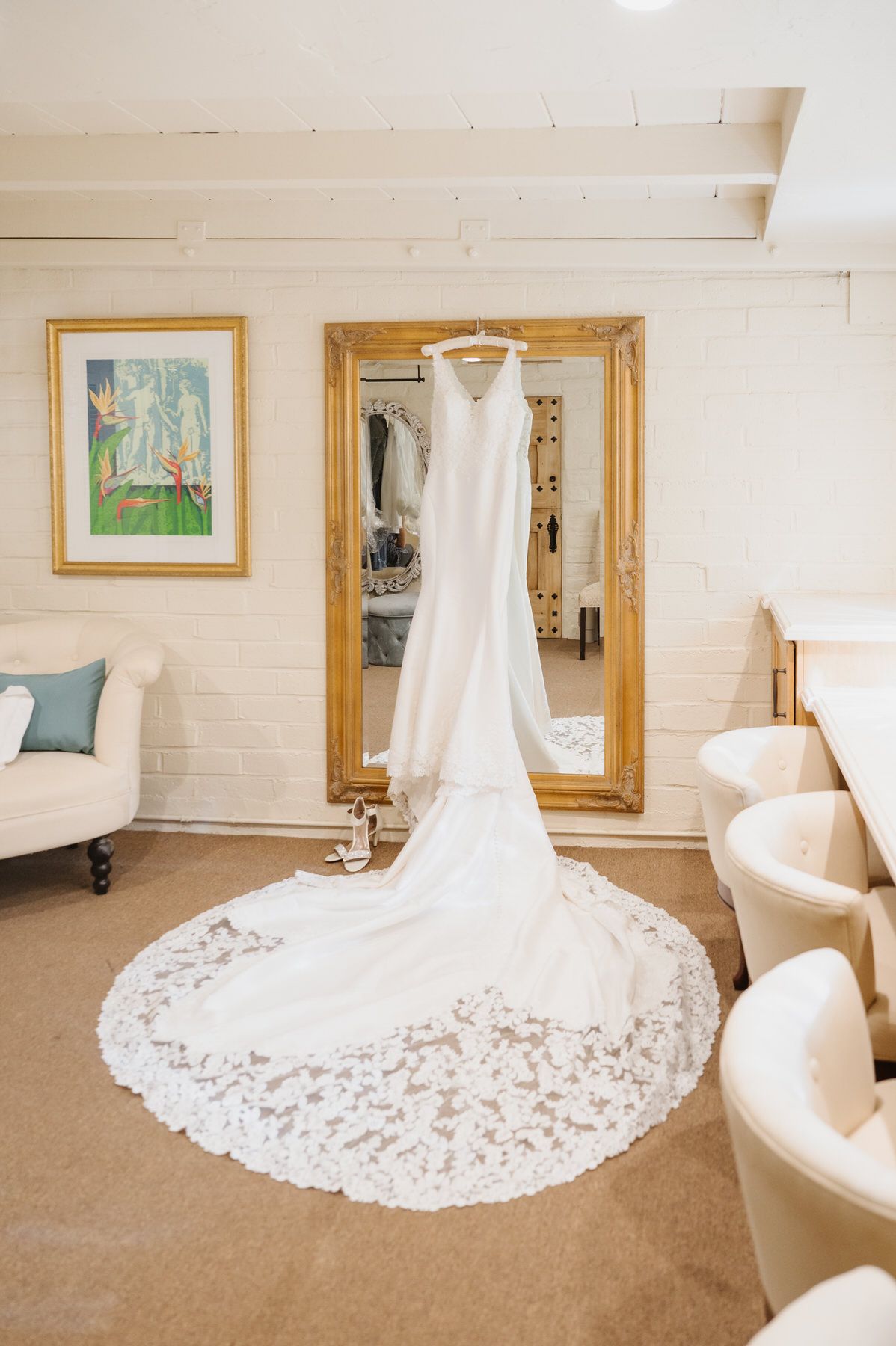 A wedding dress is hanging in front of a mirror in a room.