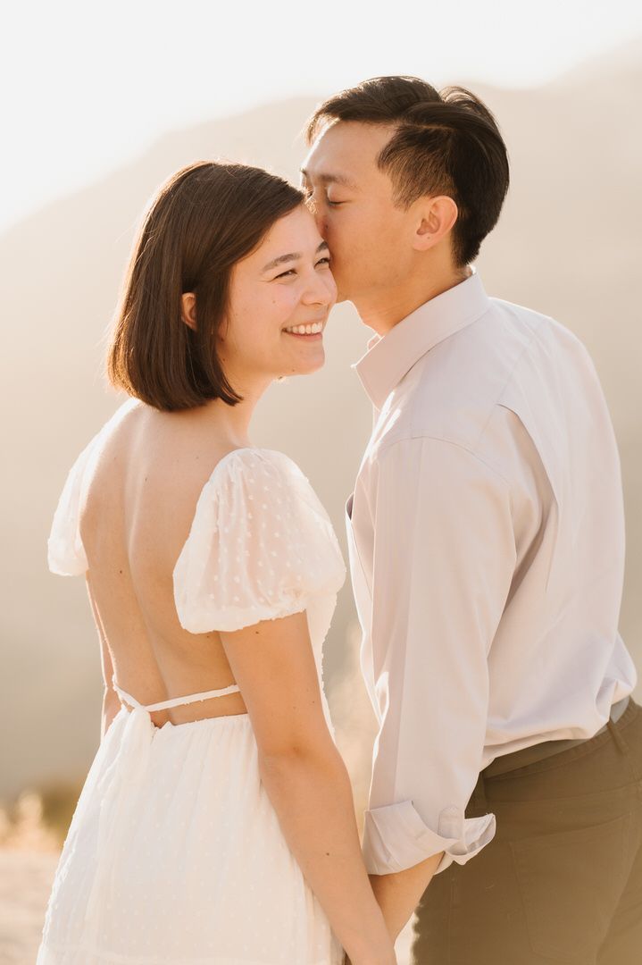 A man is kissing a woman on the forehead.