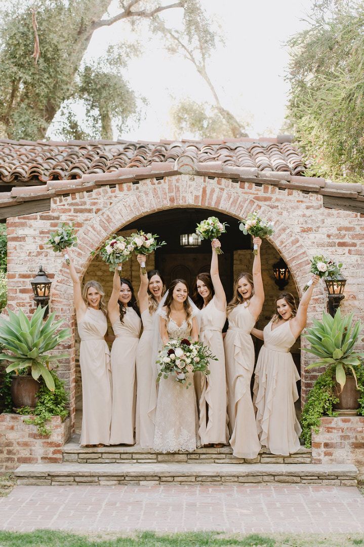 A bride and her bridesmaids are posing for a picture in front of a brick building.