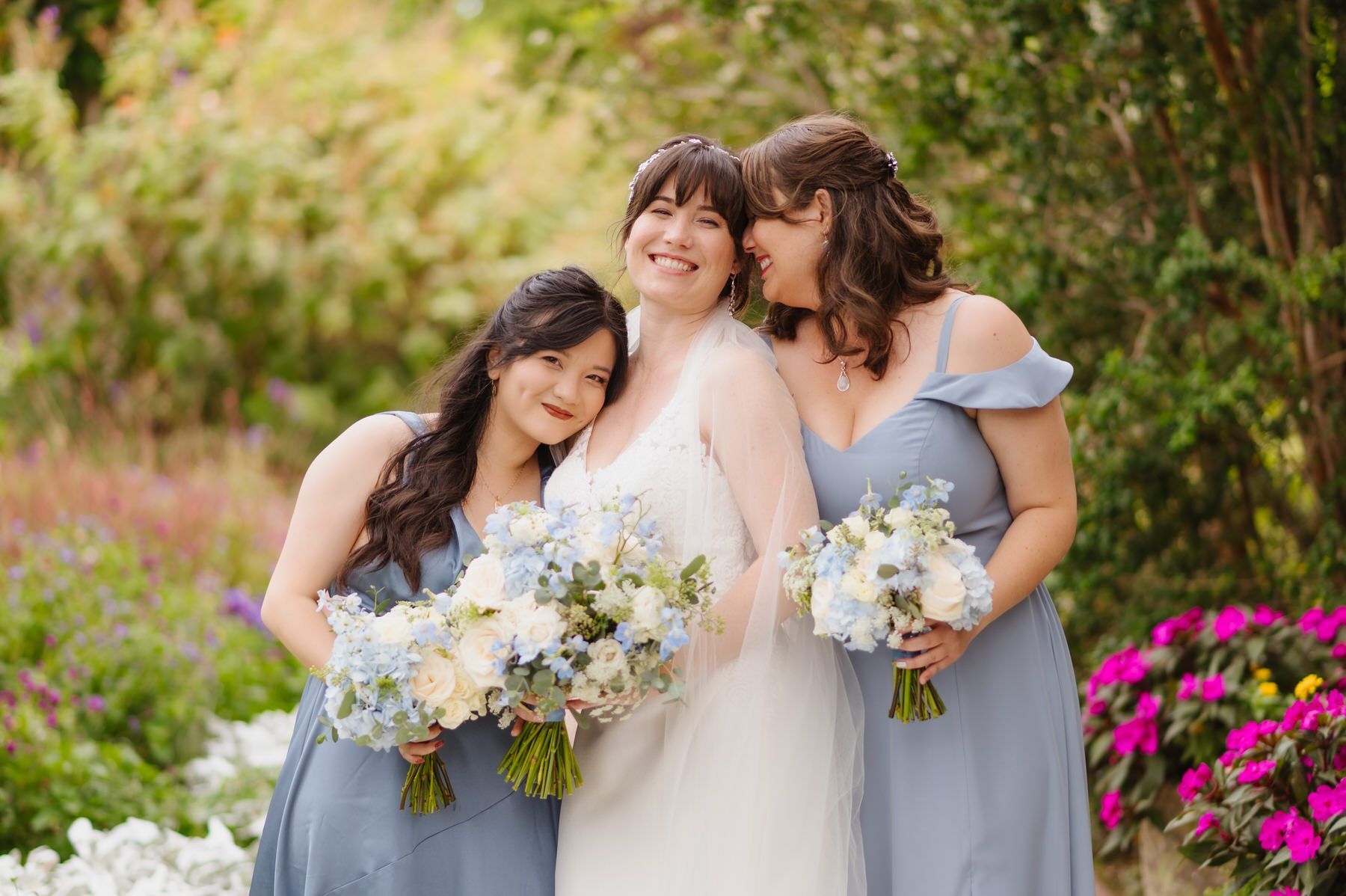 A bride and her bridesmaids are posing for a picture in a garden.