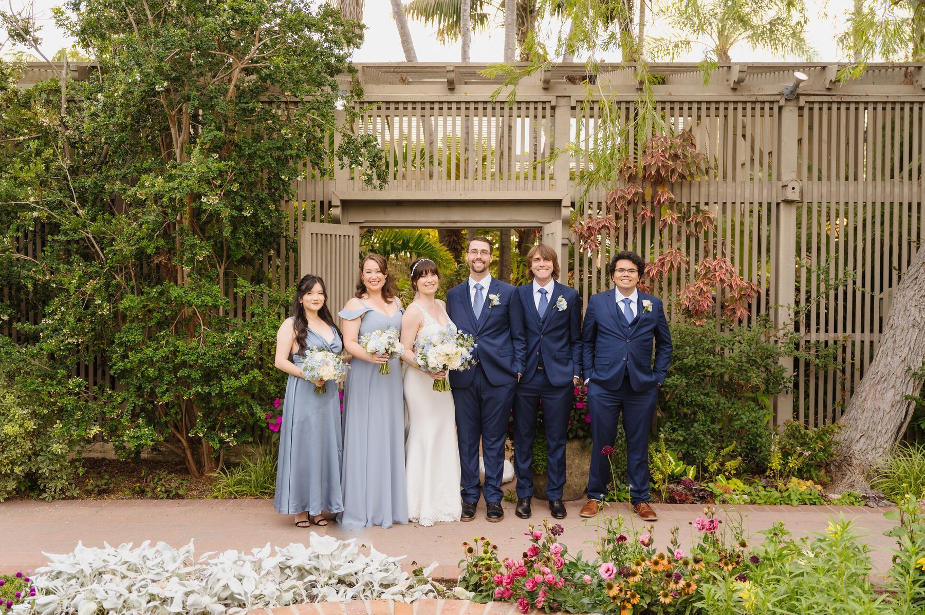 The bride and groom are posing for a picture with their wedding party.