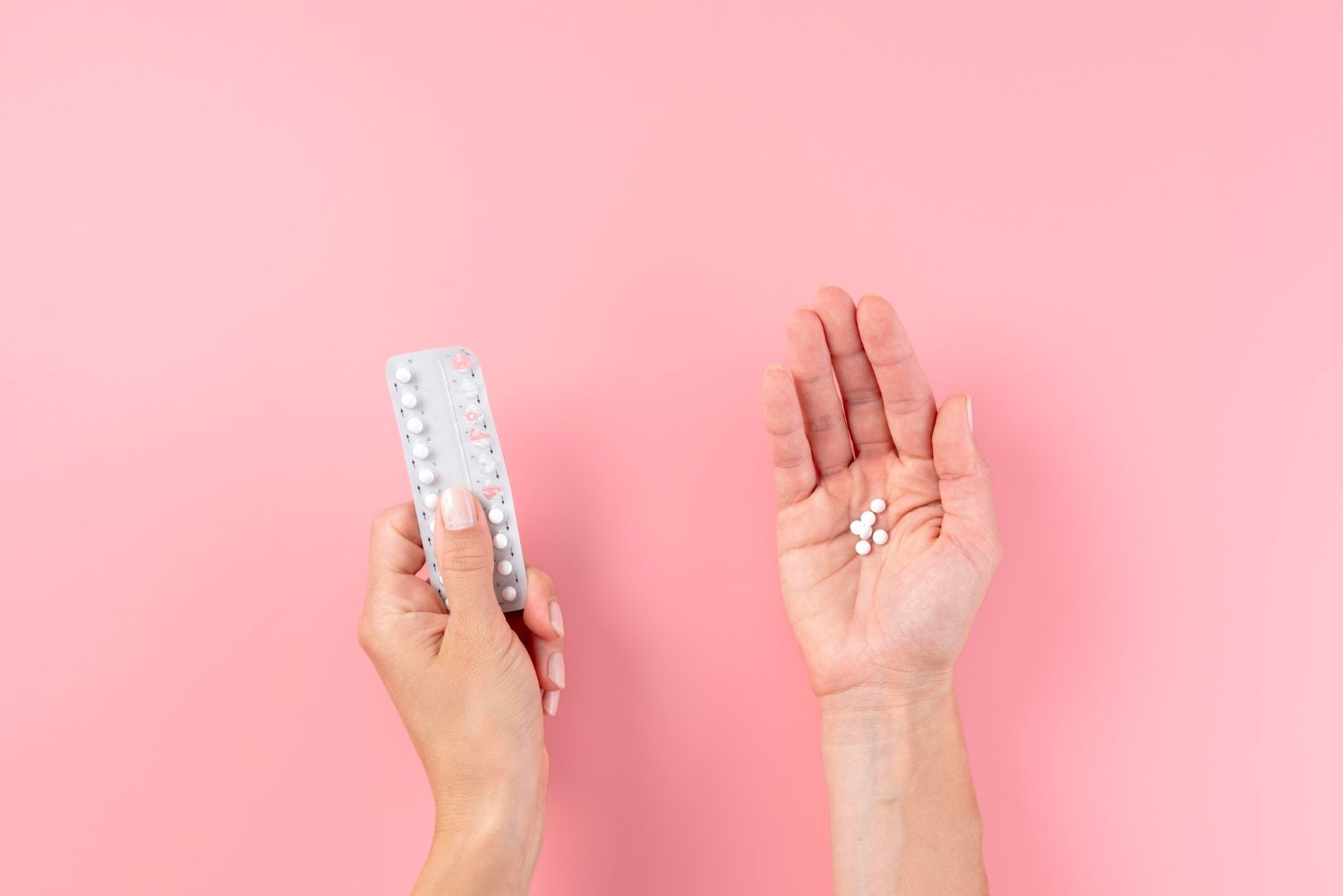 A woman is holding a contraceptive pill and a pill in her hand.